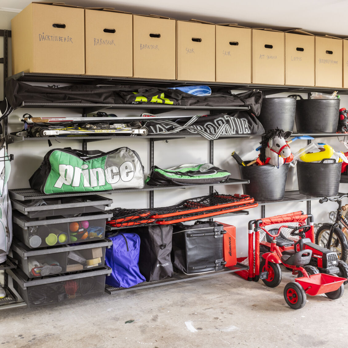 Garage med Garage+ förvaring från Elfa där det förvaras sportutrustning och leksaker på trådhyllor och i utdragbara backar.