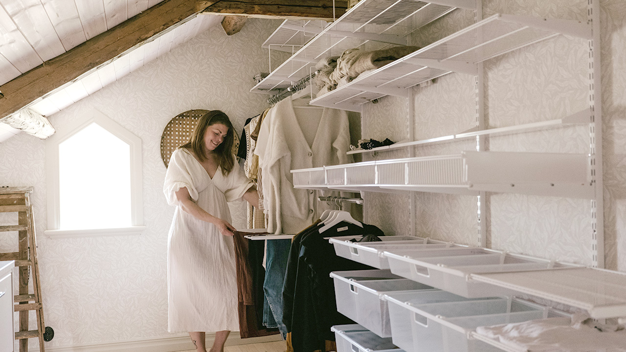 Johanna Berglund står vid sin Elfa garderob på vinden under snedtak.