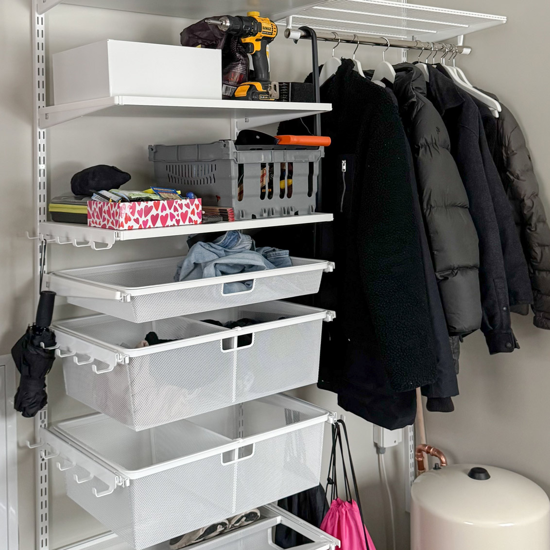 Öppen hallgarderob från Elfa med hyllor, backar och hängande kläder.