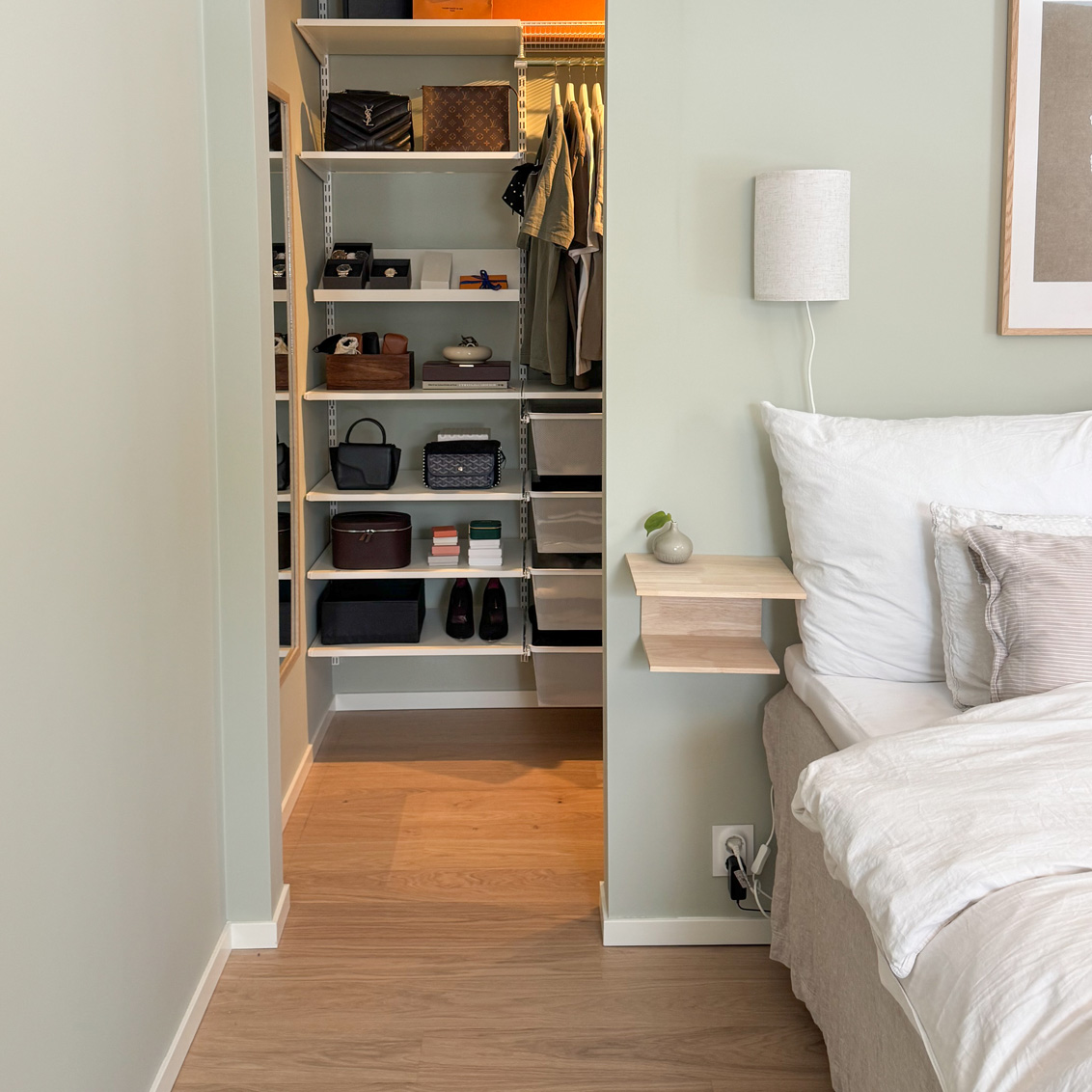 Sovrum med en walk-in closet från Elfa med skor, väskor och hängande kläder.