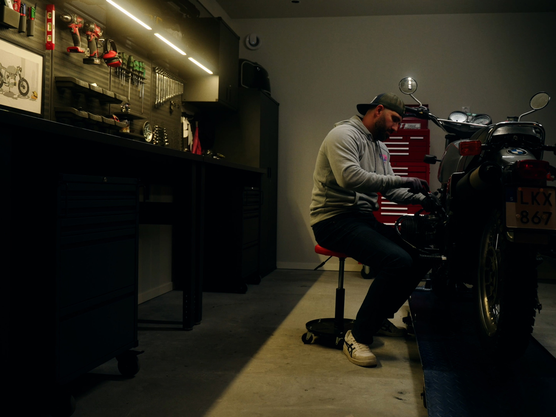 Mohammed mekar med sin motorcykel i ett garage med förvaring från Garage+ by Elfa.