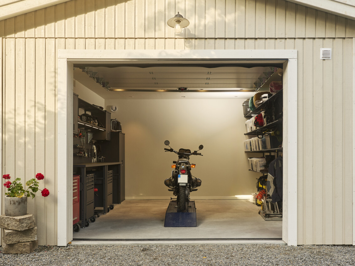 Ett öppet garage med förvaring från Garage+ by Elfa där det står en motorcykel.