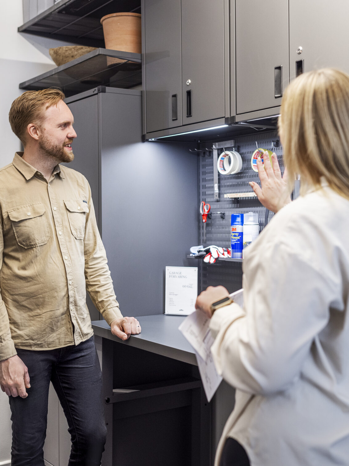 En man tittar på förvaring från Garage+ med en planeringsexpert på Studio Elfa.