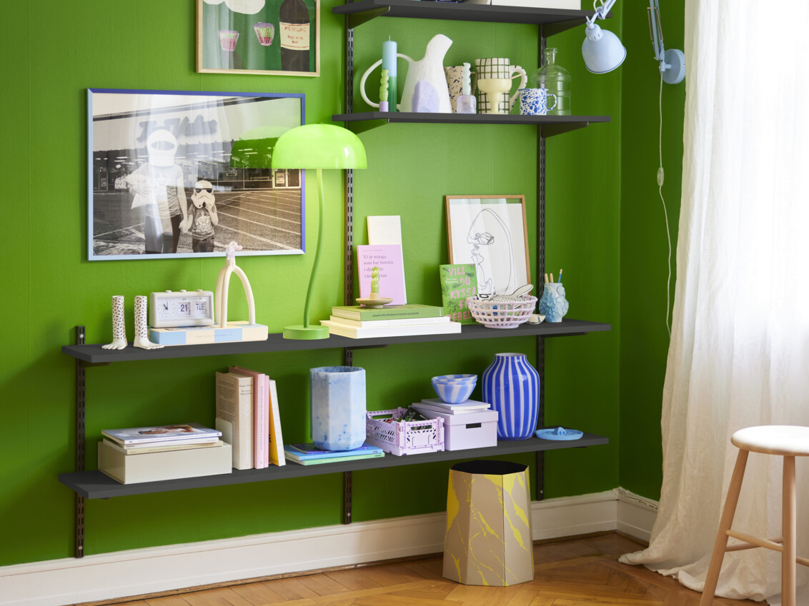 Olohuone, jossa on limenvihreä seinä ja harmaa Sparring by Elfa -kirjahylly, jossa on värikkäitä koristeita.
