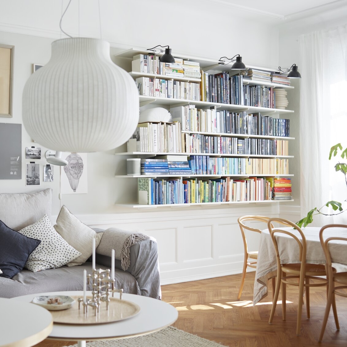 Olohuone, jossa on valkoinen Sparring by Elfa -kirjahylly, jossa kirjat on lajiteltu värien mukaan.