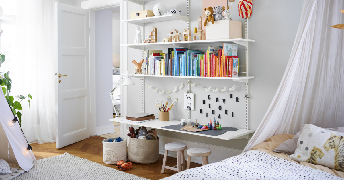 Pokój dziecięcy z półką pełną książek Sparring by Elfa w kolorze białym, z dolną półką pełniącą funkcję biurka.