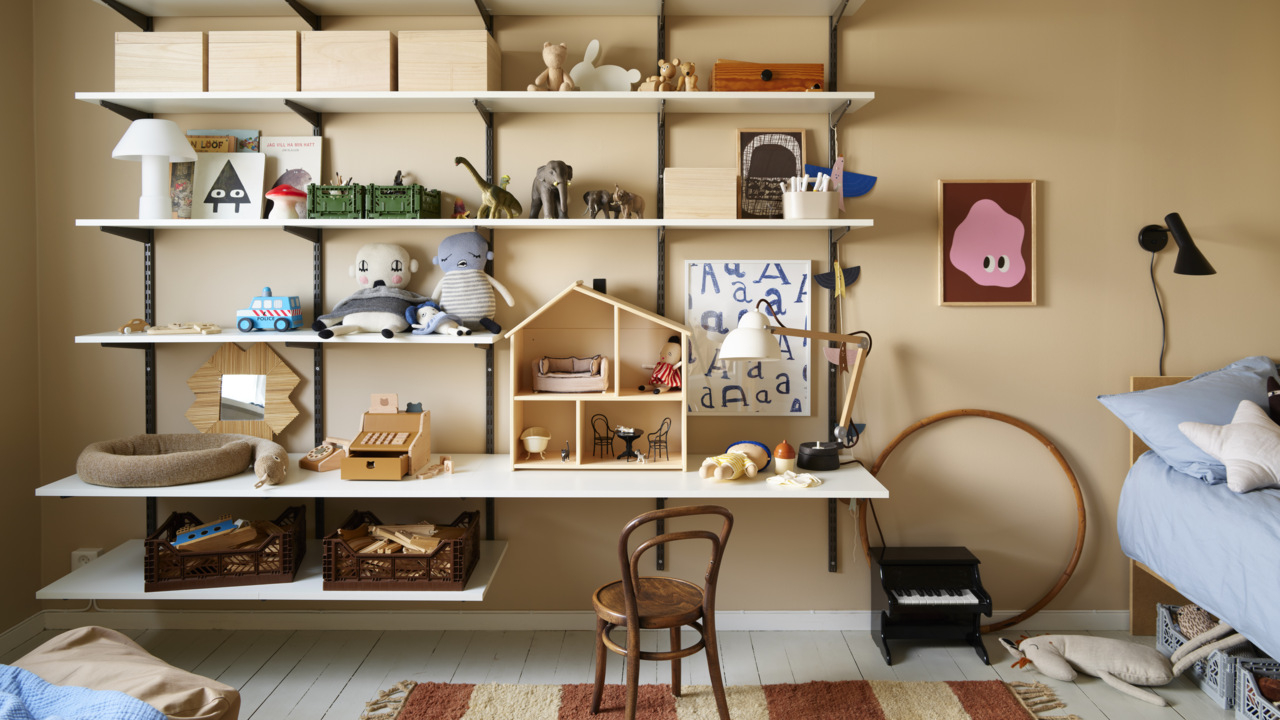 Pokój dziecięcy z biurkiem Classic by Elfa z półkami pełnymi zabawek.