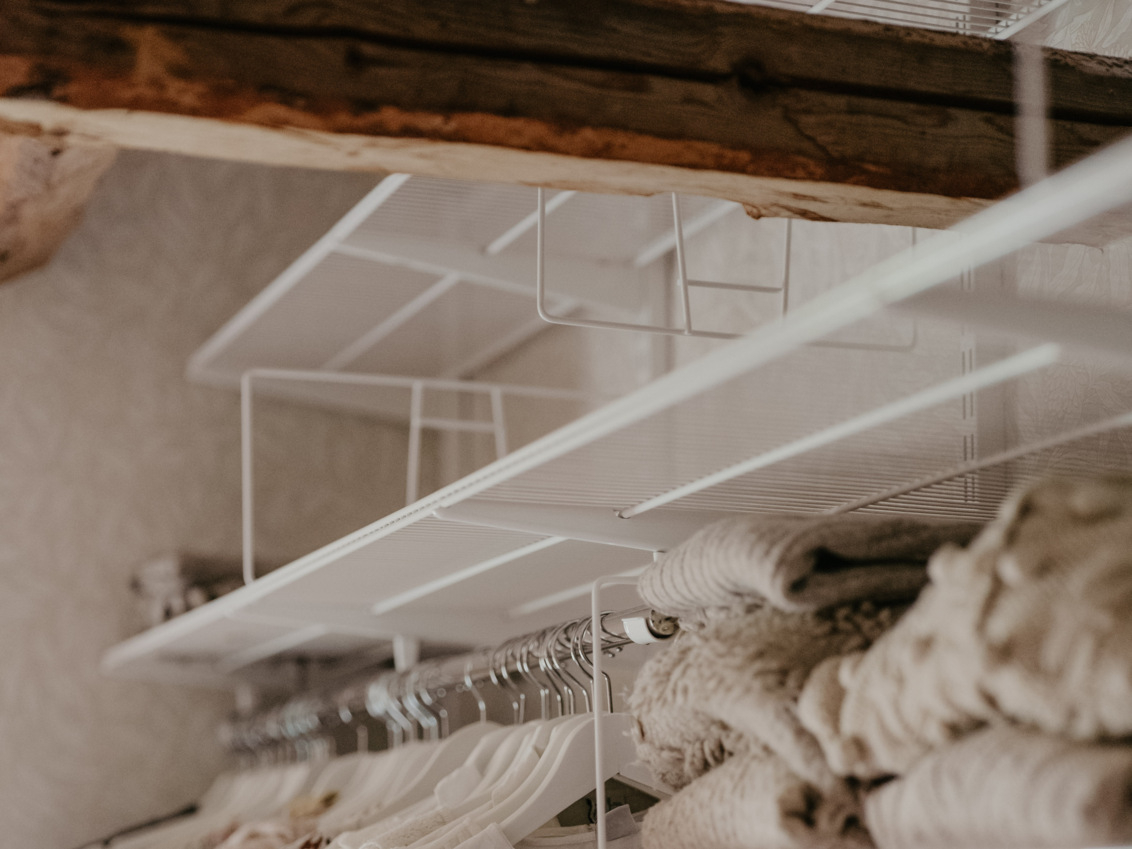 Loft with roof joists featuring Classic by Elfa storage in white.