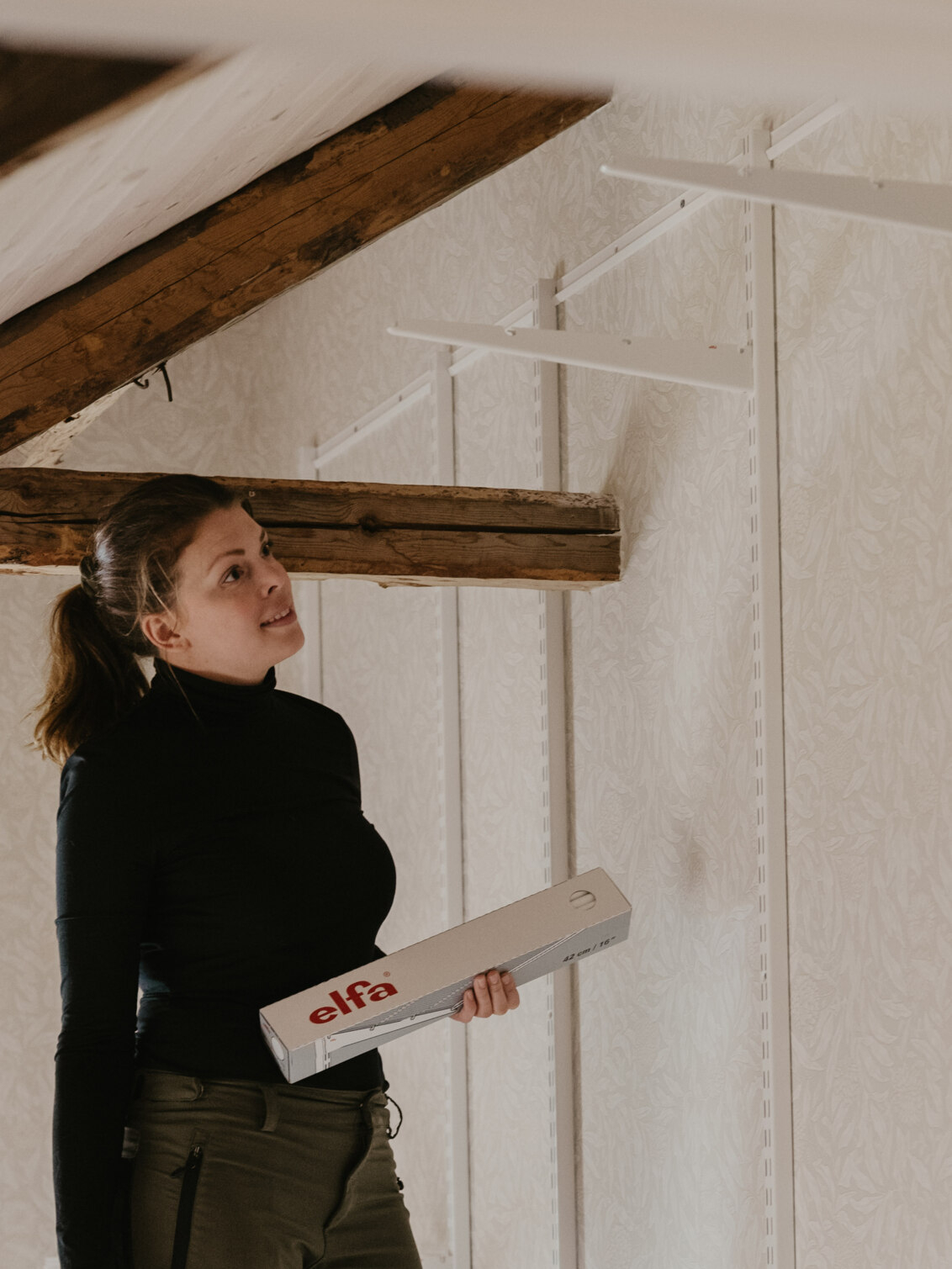 Johanna Berglund monterer oppbevaring fra Classic by Elfa på loftet under skråtaket.