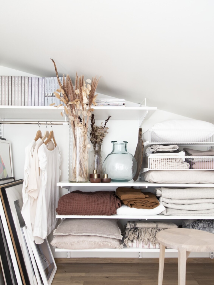 Niki Brantmark sitter på golvet på en vind med förvaring från Classic by Elfa under snedtak.