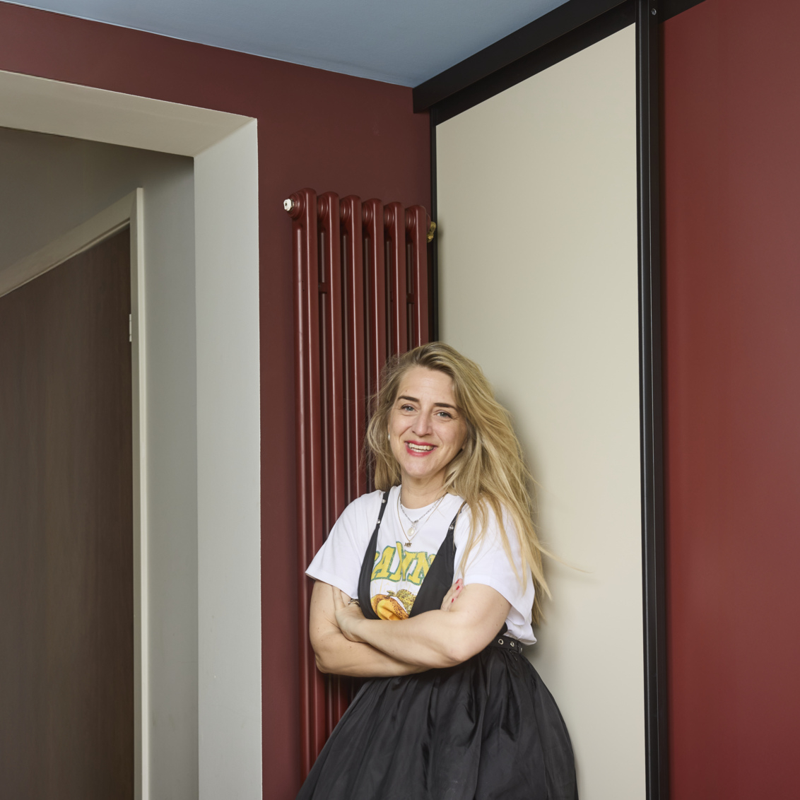 Caroline stoi w przedpokoju przed szafą z drzwiami przesuwnymi Elfa.