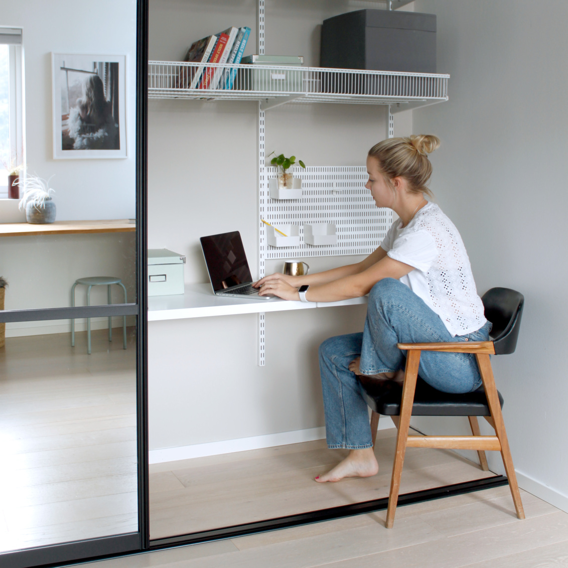 Nainen istuu kotitoimistossa, jossa on säilytystilaa ja liukuovia, joissa on Elfan peili.