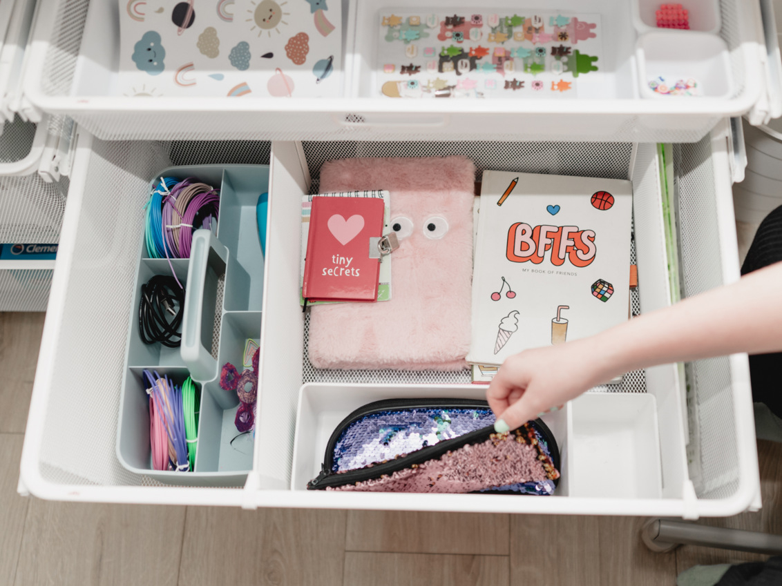 Wysuwany biały kosz mesh Classic by Elfa z notatnikami, piórnikiem i opaską na włosy.