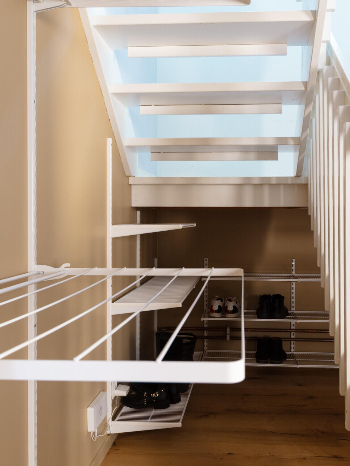 Området under trappen, hvor der hænger tørrestativer og trådhylder fra Elfa med sko på.