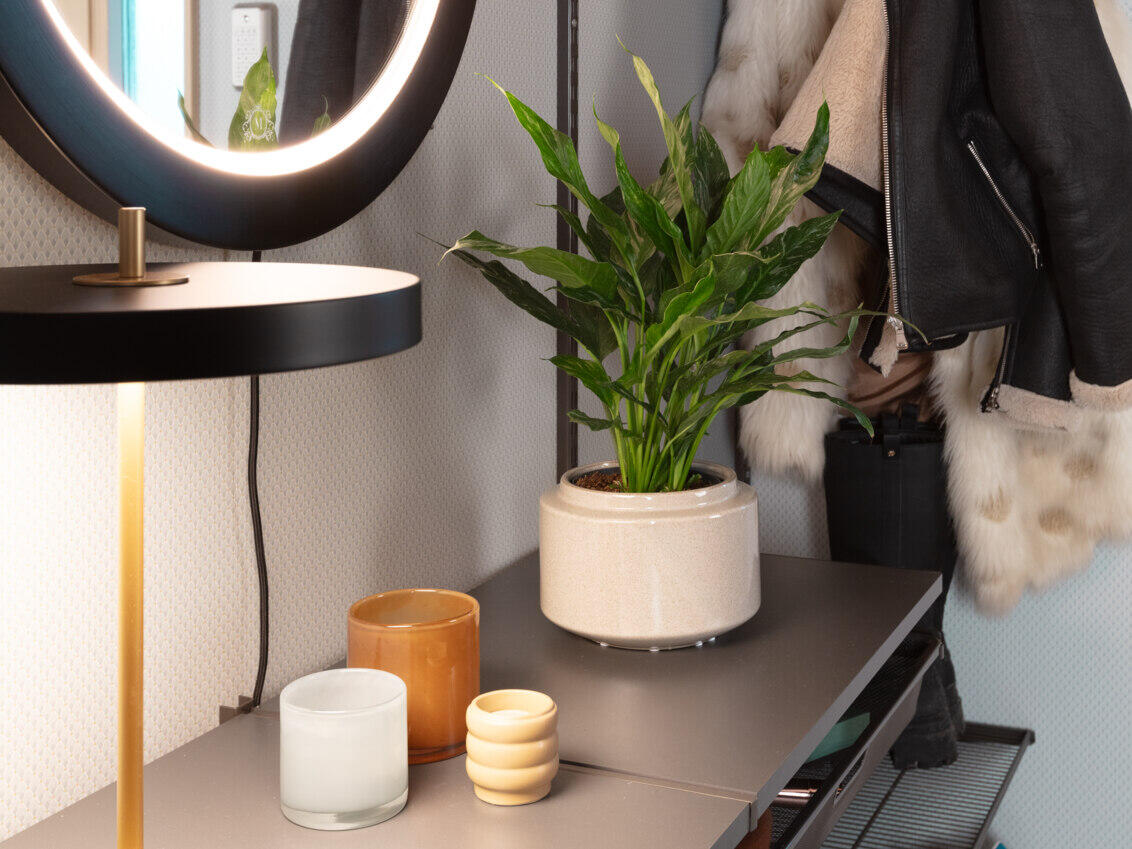 Opbevaring fra Elfa i grå med pyntegenstande og et spejl med indbygget belysning.