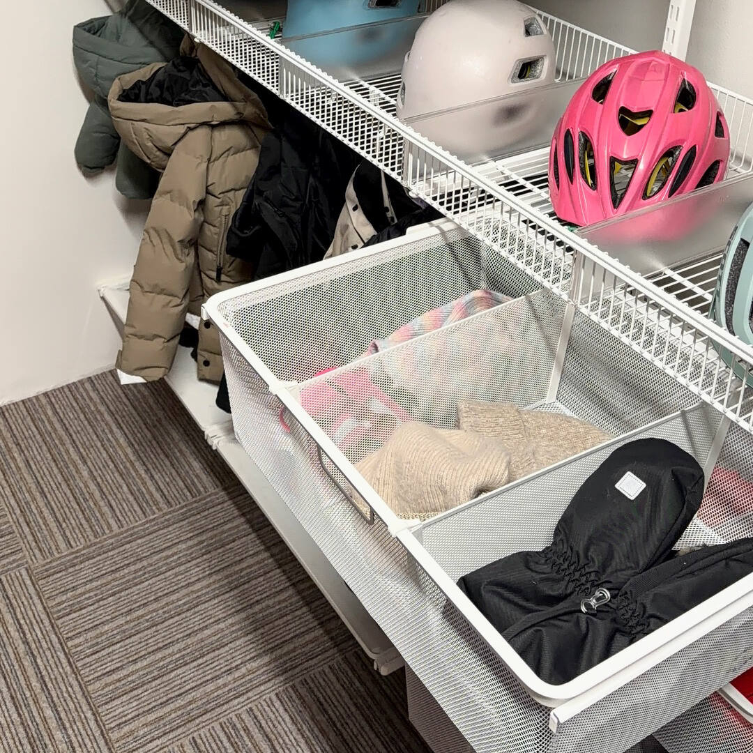 Hallförvaring från Classic by Elfa med trådhyllkorgar och utdragbara meshbackar där det förvaras hjälmar, mössor och vantar.