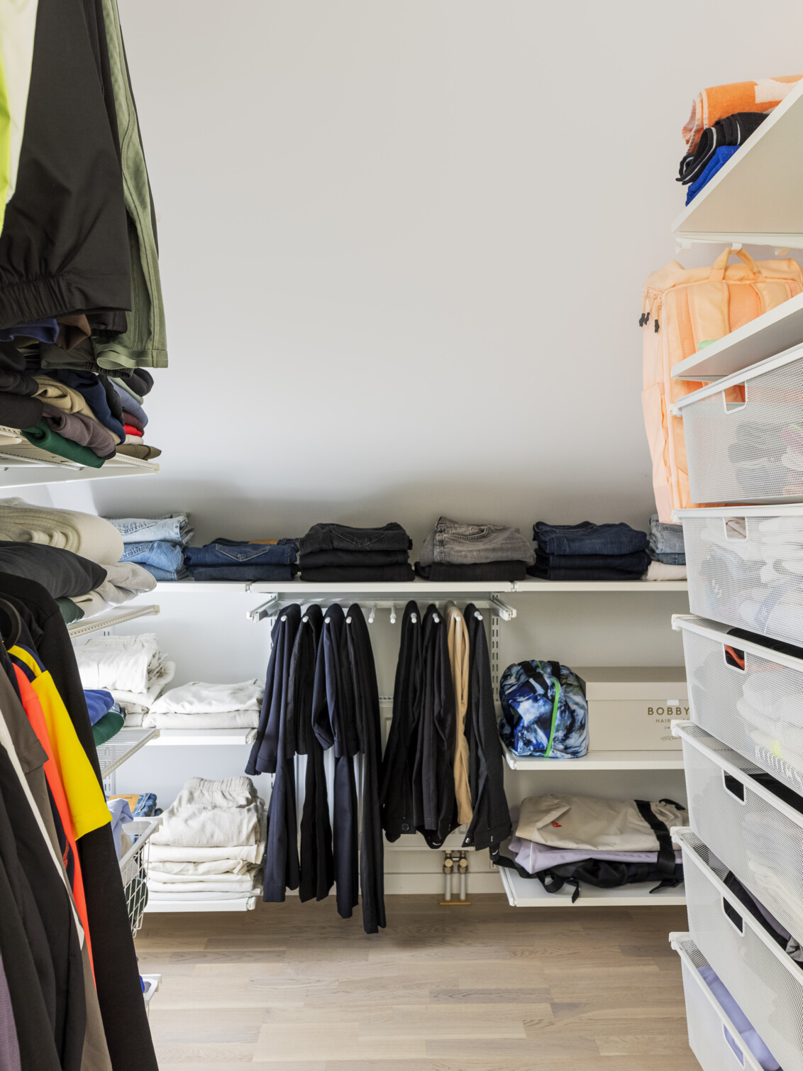 Klädkammare med förvaring från Classic by Elfa med hängande kläder, utdragbara meshbackar och en byxhängare.