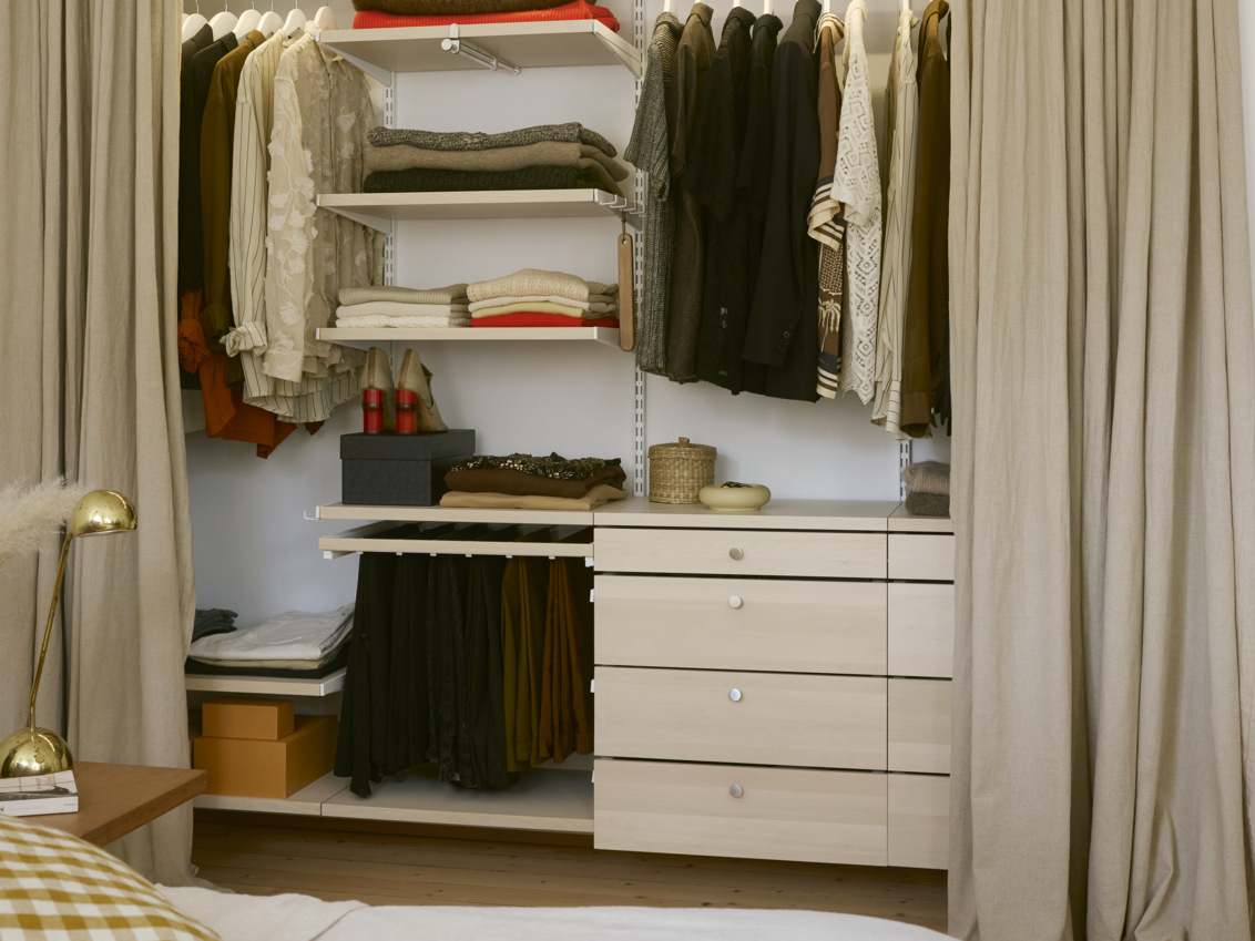 Kläder och accessoarer i en Classic by Elfa garderob i vitt och björk.