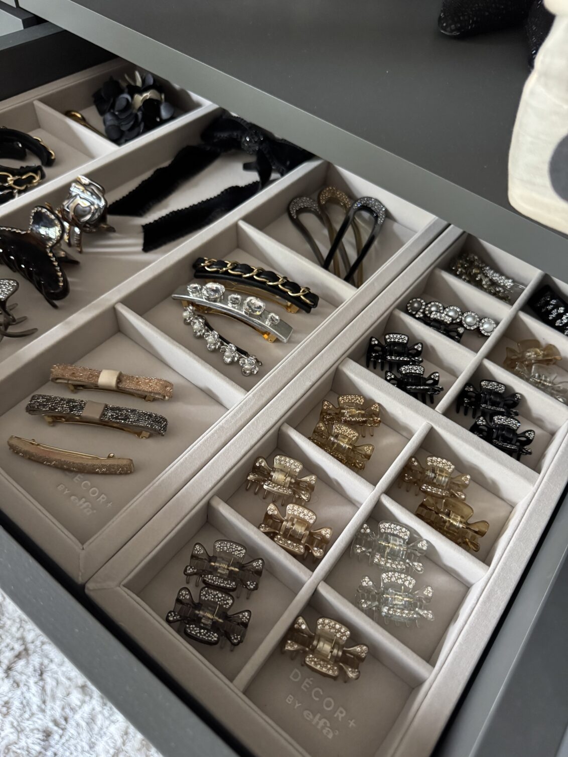 Öppen låda från Décor+ by Elfa med accessoarbricka fylld med smycken och hårklämmor.