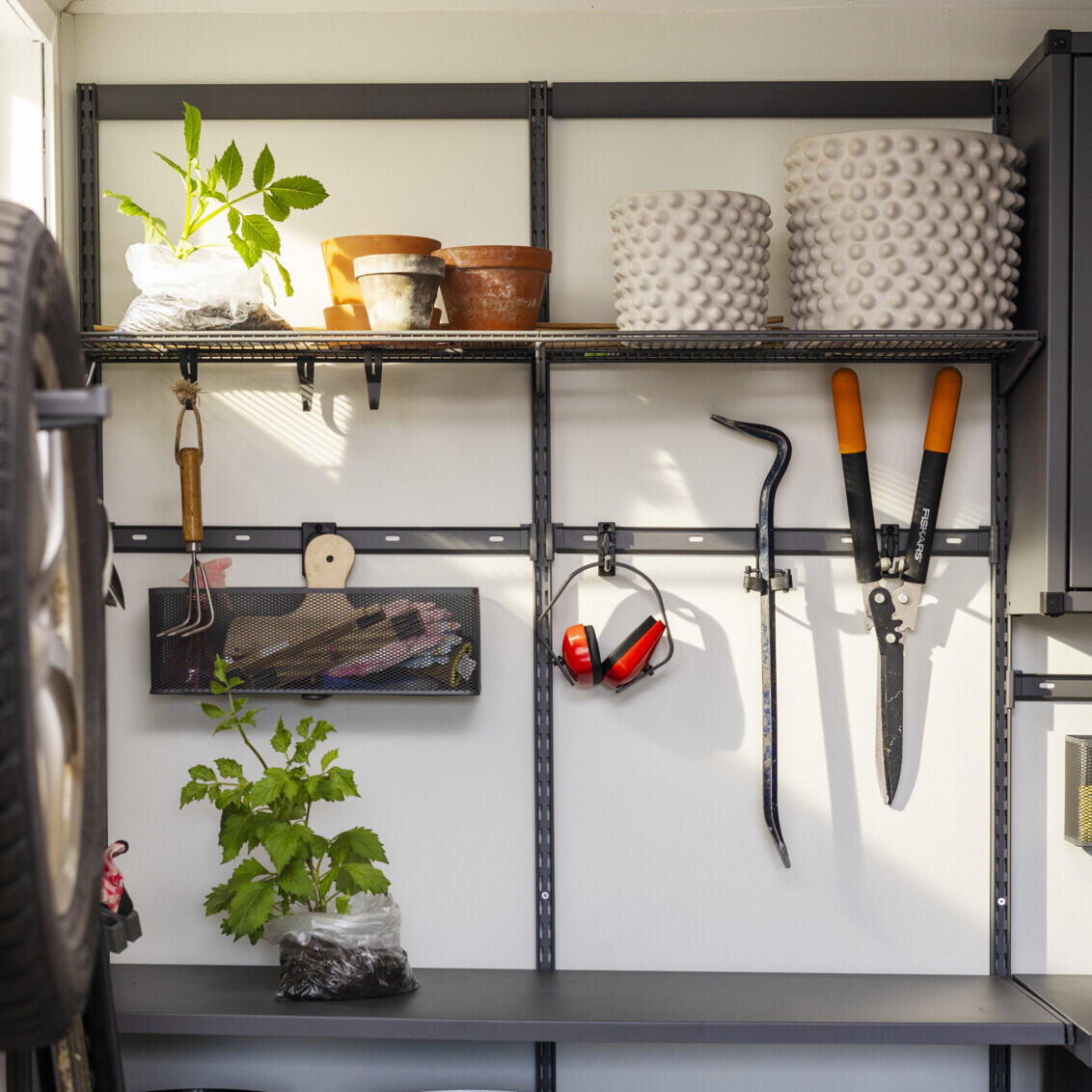 Garage med Garage+ förvaring från Elfa där det förvaras växter och trädgårdsverktyg.