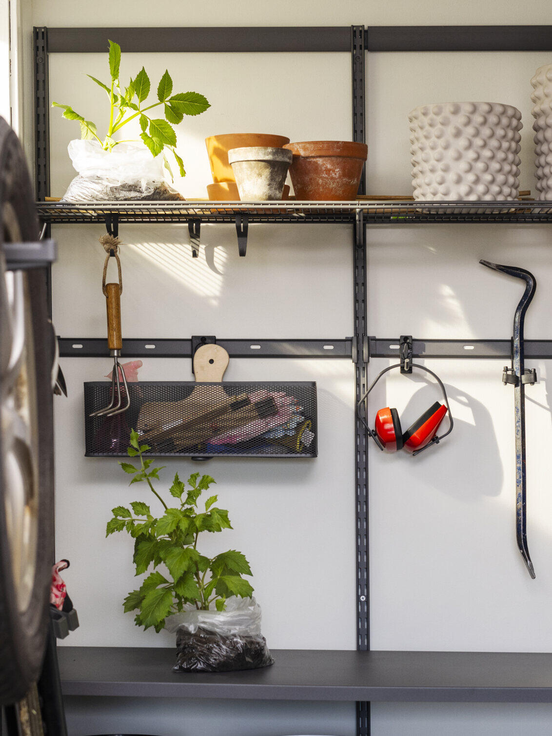 Garage med Garage+ förvaring från Elfa där det förvaras växter och trädgårdsverktyg.
