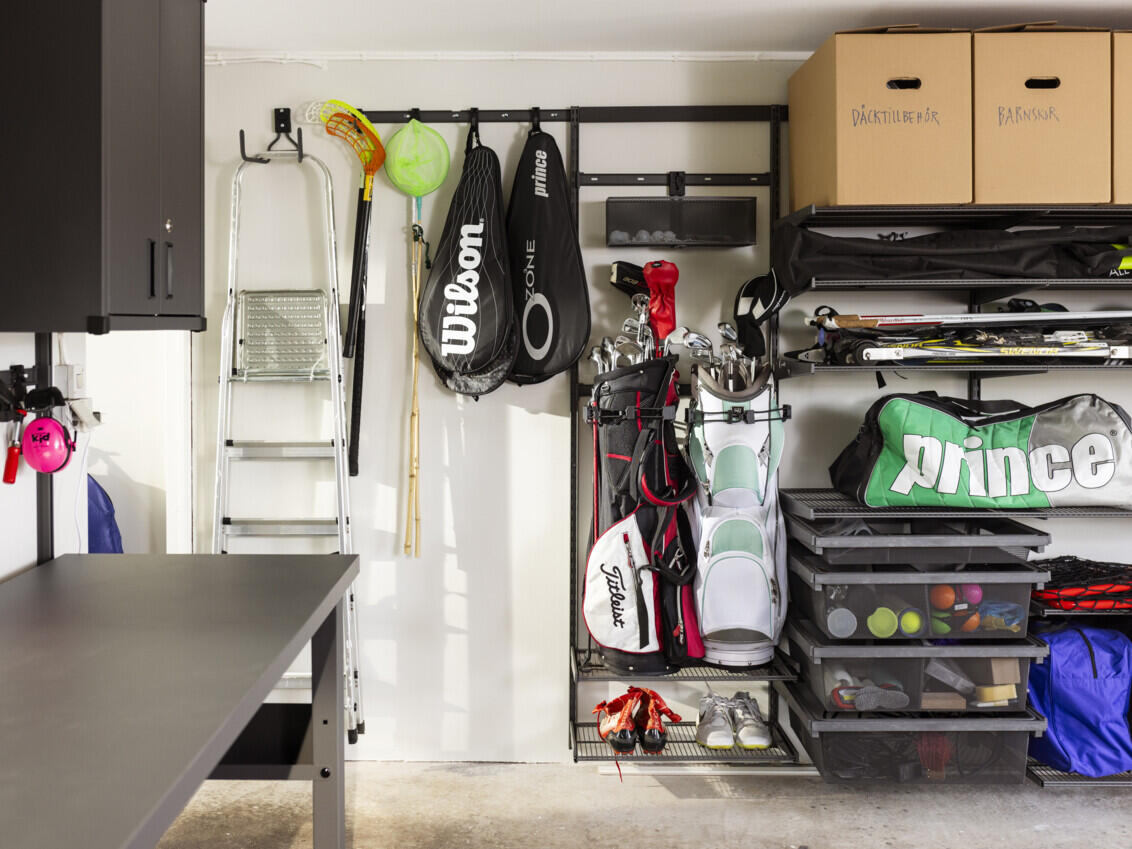 Garage med Garage+ förvaring från Elfa där det hänger sportutrustning som golfklubbor, tennisracket  och skidor.