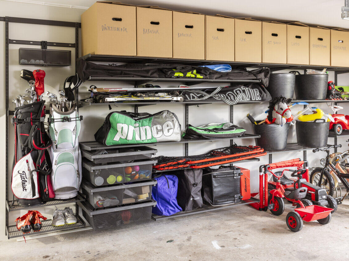 Garage with Garage+ storage from Elfa used for storing sports equipment and toys on shelves and drawers with gliding frames.