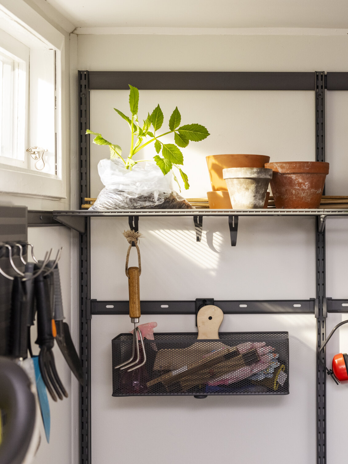 Garasje med Garage+ oppbevaring fra Elfa med trådhyller og oppbevaringslist der det oppbevares krukker og hageredskaper.