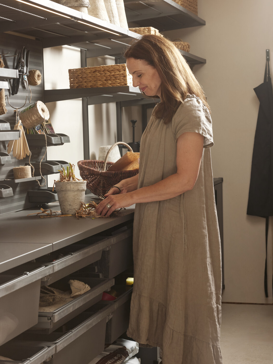 Carin planterar om växter i ett förråd med förvaring från Garage+ by Elfa.