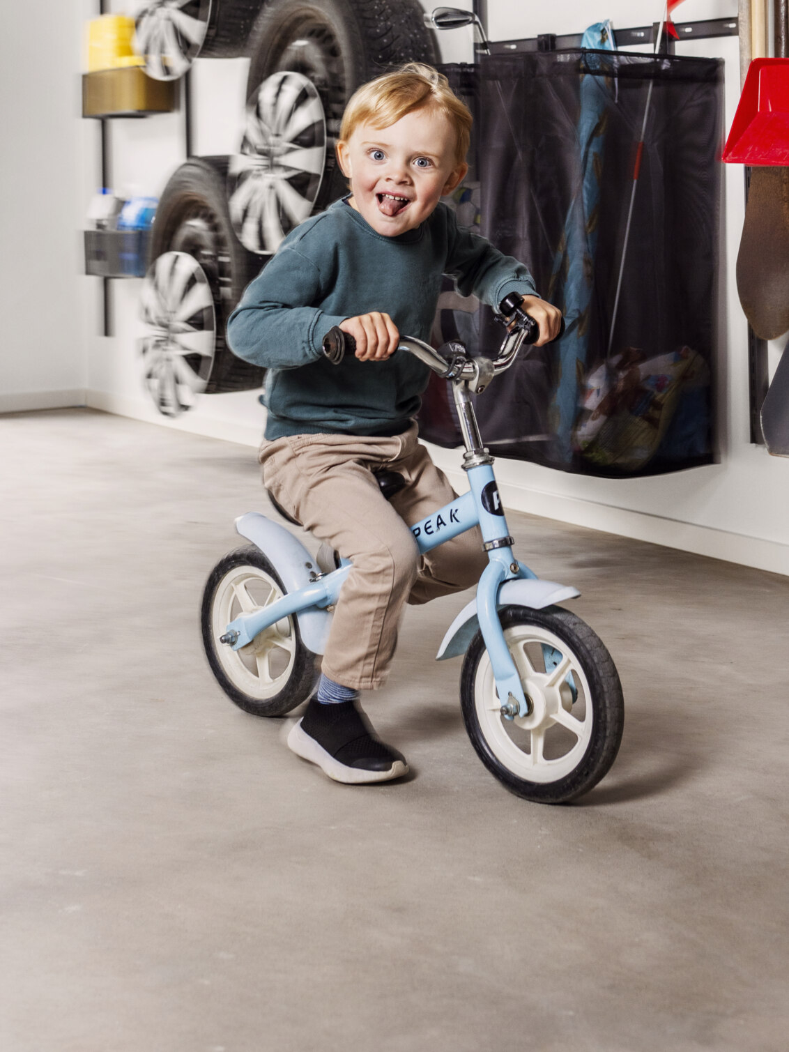 Pojke cyklar i ett garage med förvaring från Garage+ by Elfa.