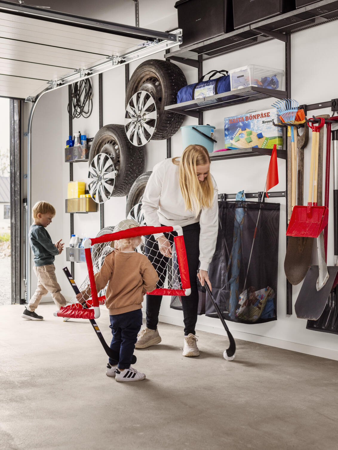En småbarnsfamilj spelar bandy i ett garage med Garage+ by Elfa förvaring.