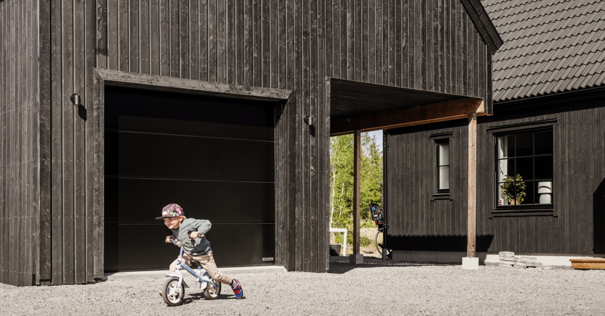 En pojke cyklar på gårdsplanen utanför ett garage.