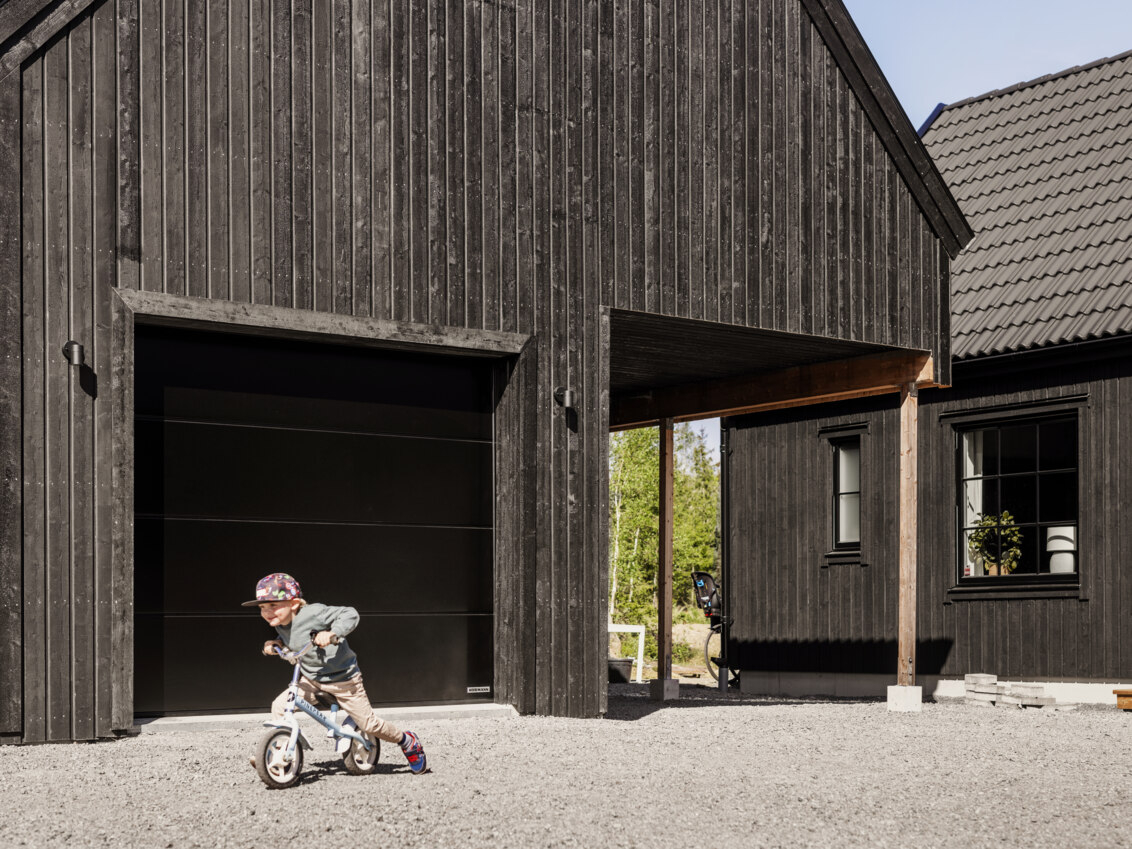 A little boy riding a bike outside a garage.
