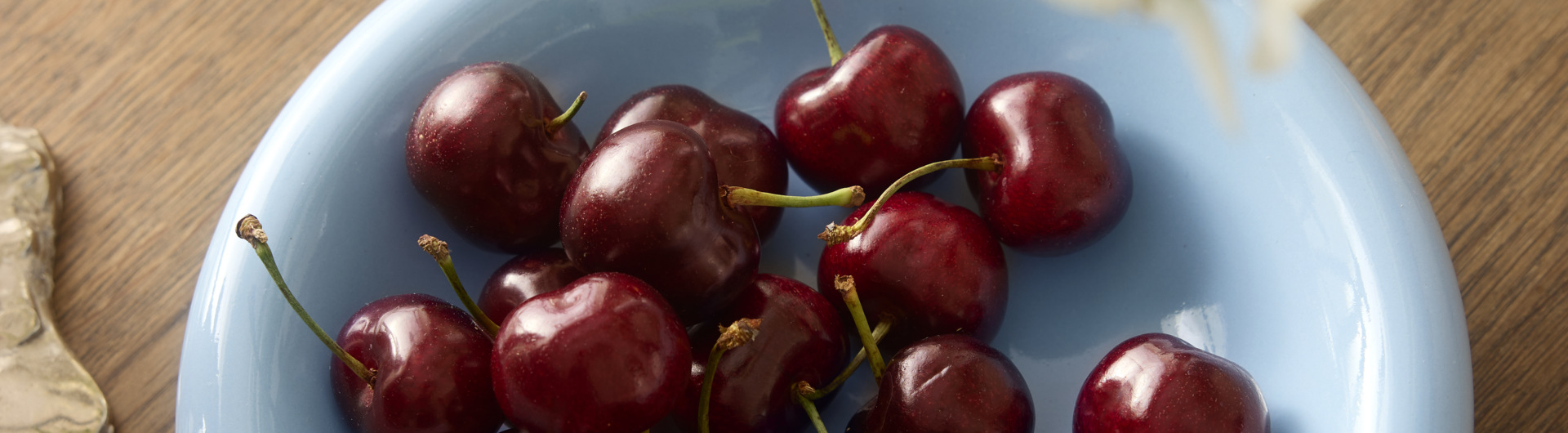 Jasnoniebieski talerz wypełniony wiśniami.