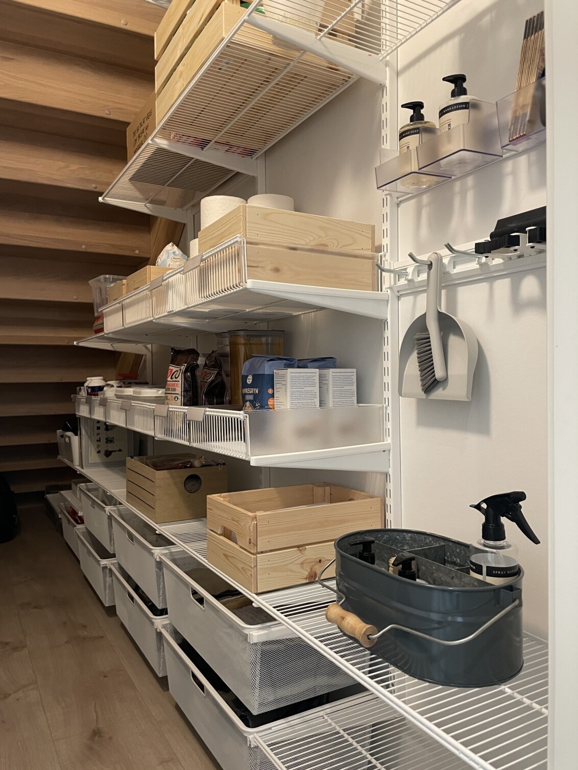 Skafferi under en trappa med förvaring från Elfa där det förvaras torrvaror och städsaker.