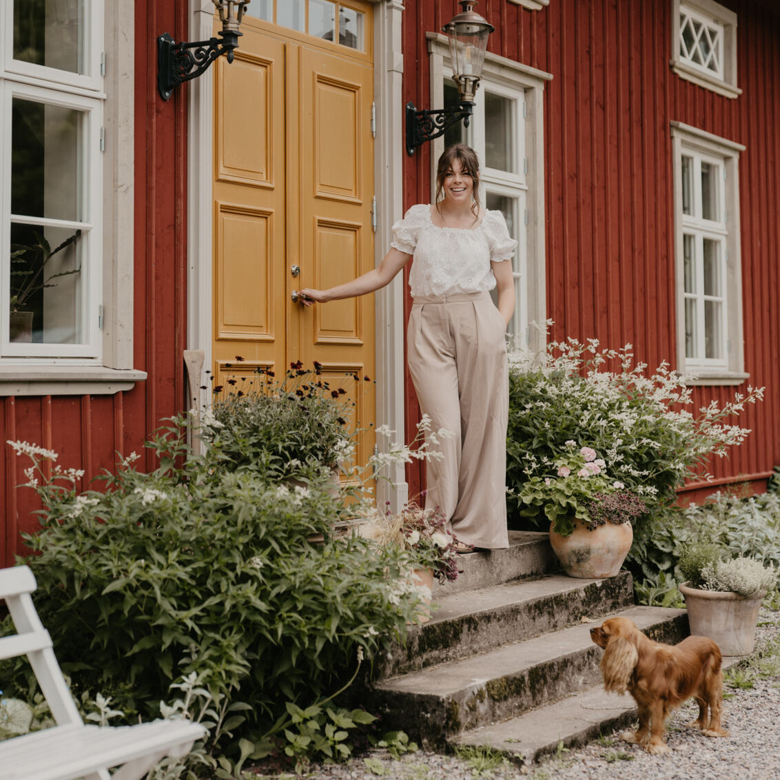 En kvinna står utanför ett lantligt hus