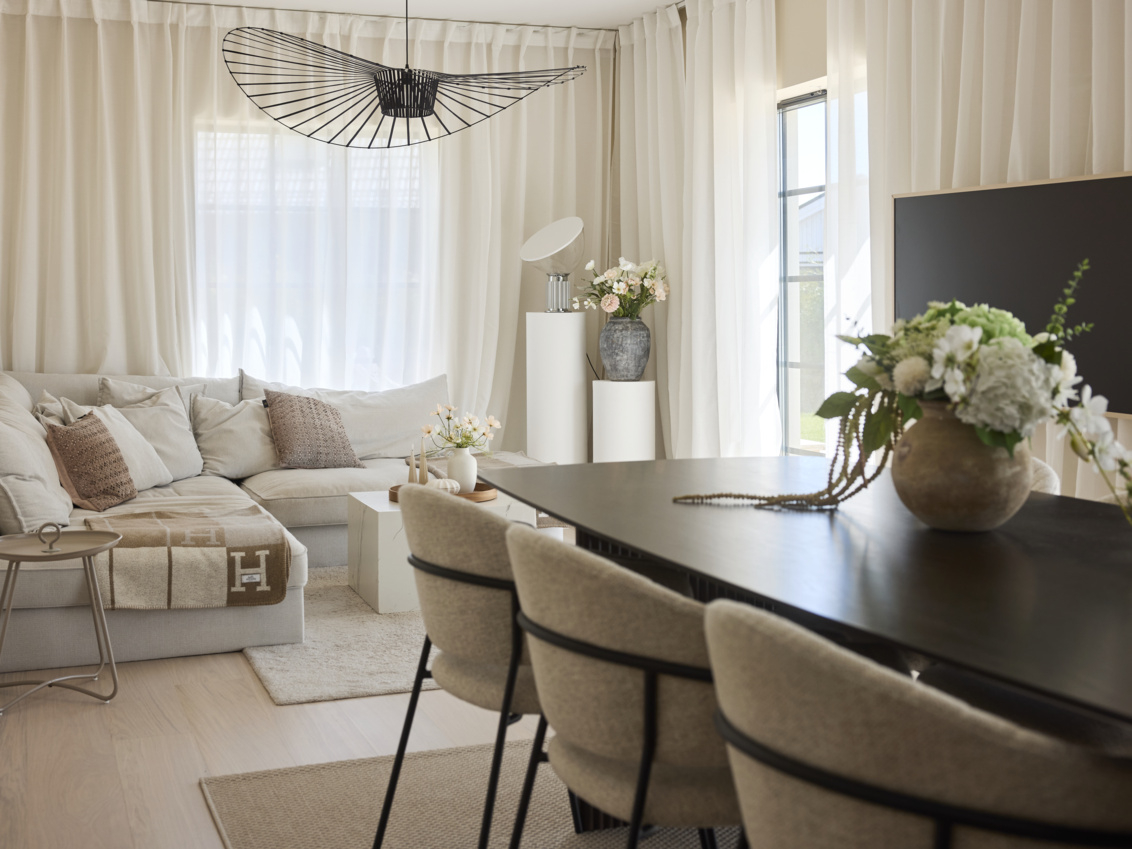 Pokój dzienny w jasnych odcieniach ze stołem do jadalni z ciemnego drewna.