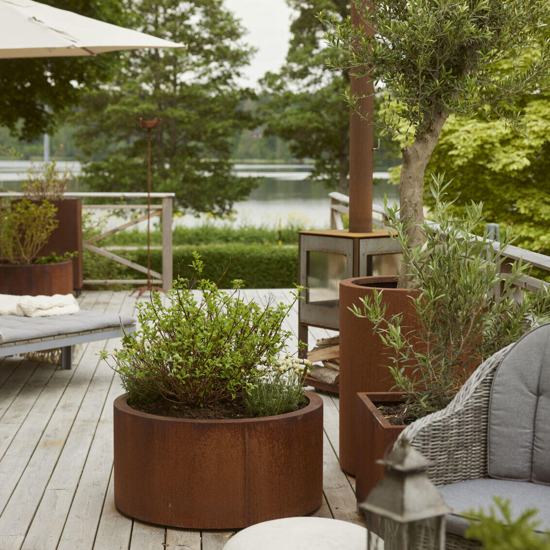 Wooden decking with plants and lounge chairs overlooking the lake.