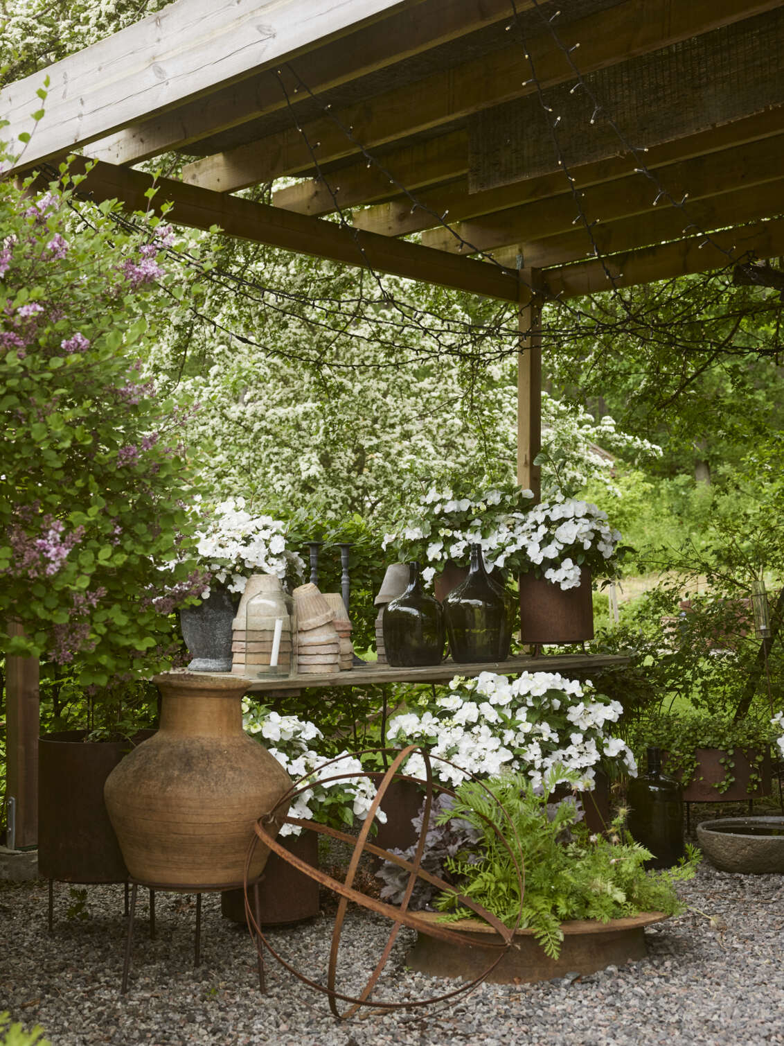 Potter i ulike størrelser oppstilt på et hagebord.