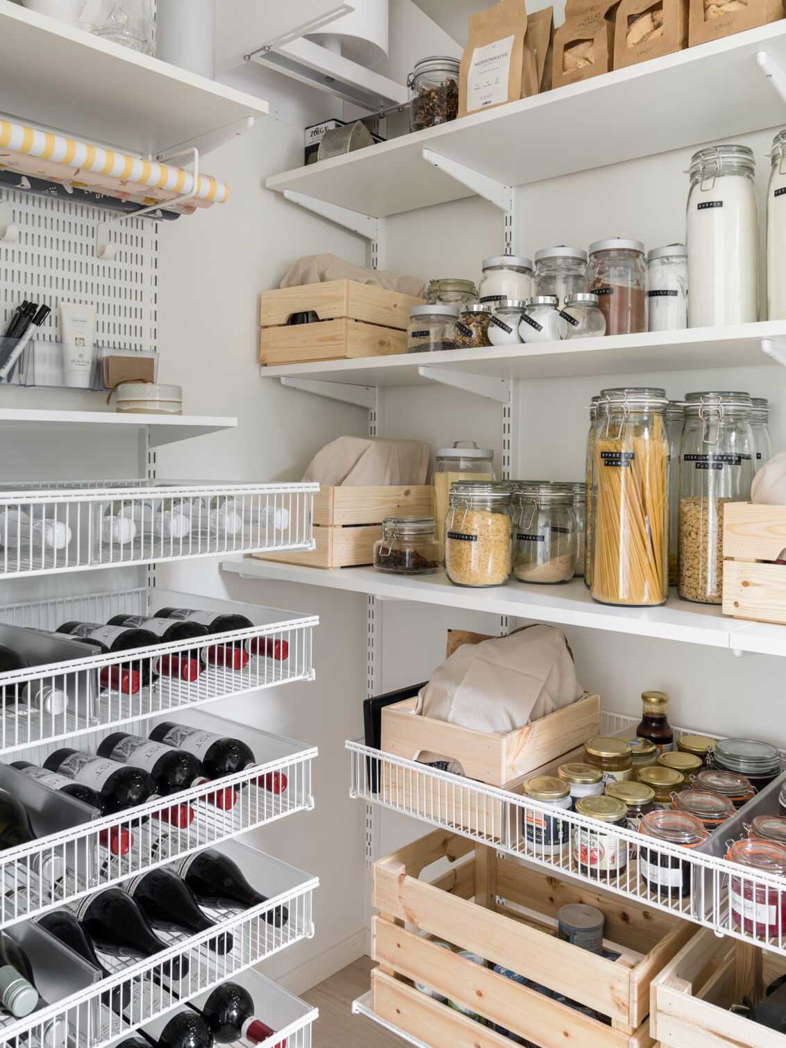Skafferi med Classic by Elfa förvaring med torrvaror på hyllorna och vinflaskor i trådhyllkorgarna.