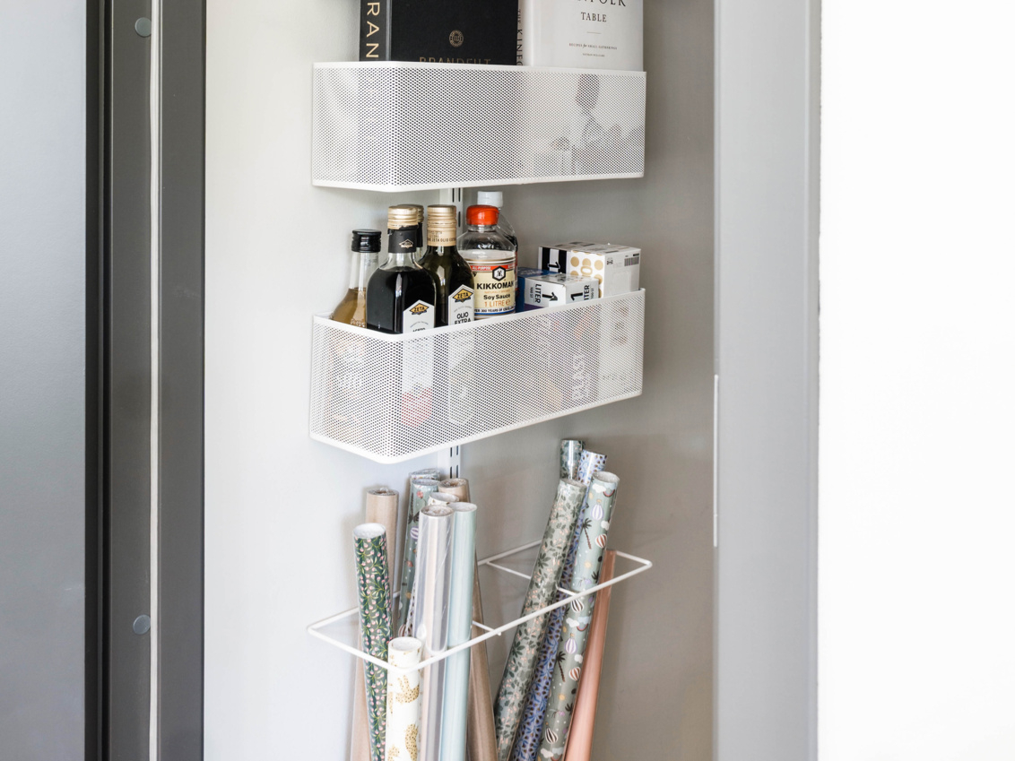 Classic by Elfa -oven säilytystila, jossa on verkkokoreja kirjoille ja elintarvikkeille sekä lahjapaperilla varustettu lahjapakkausteline.