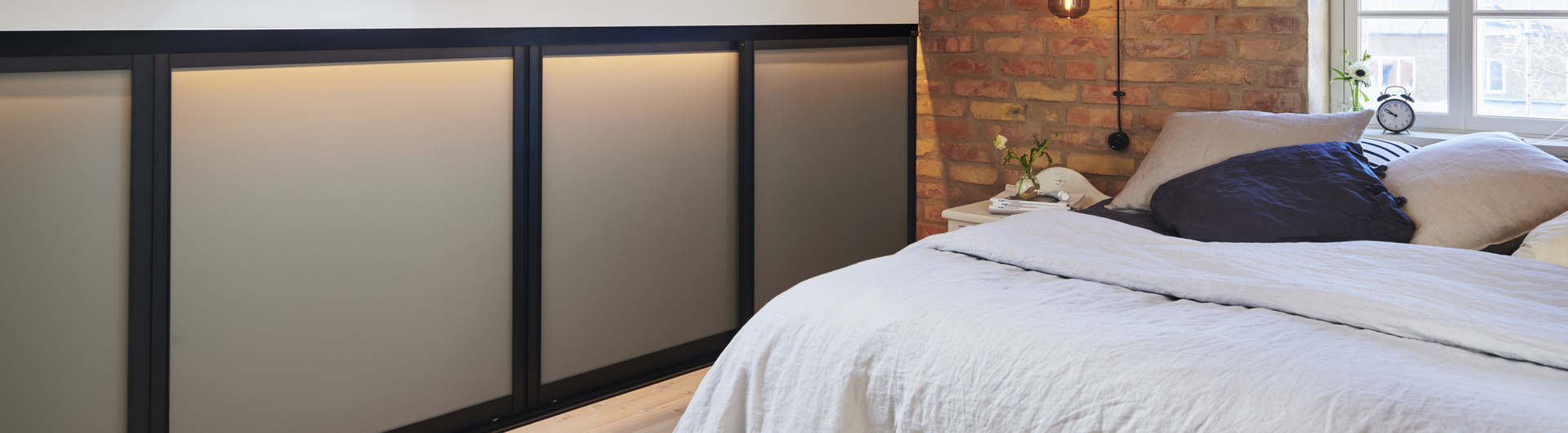 Sovrum med en låg garderob med skjutdörrar från Elfa.