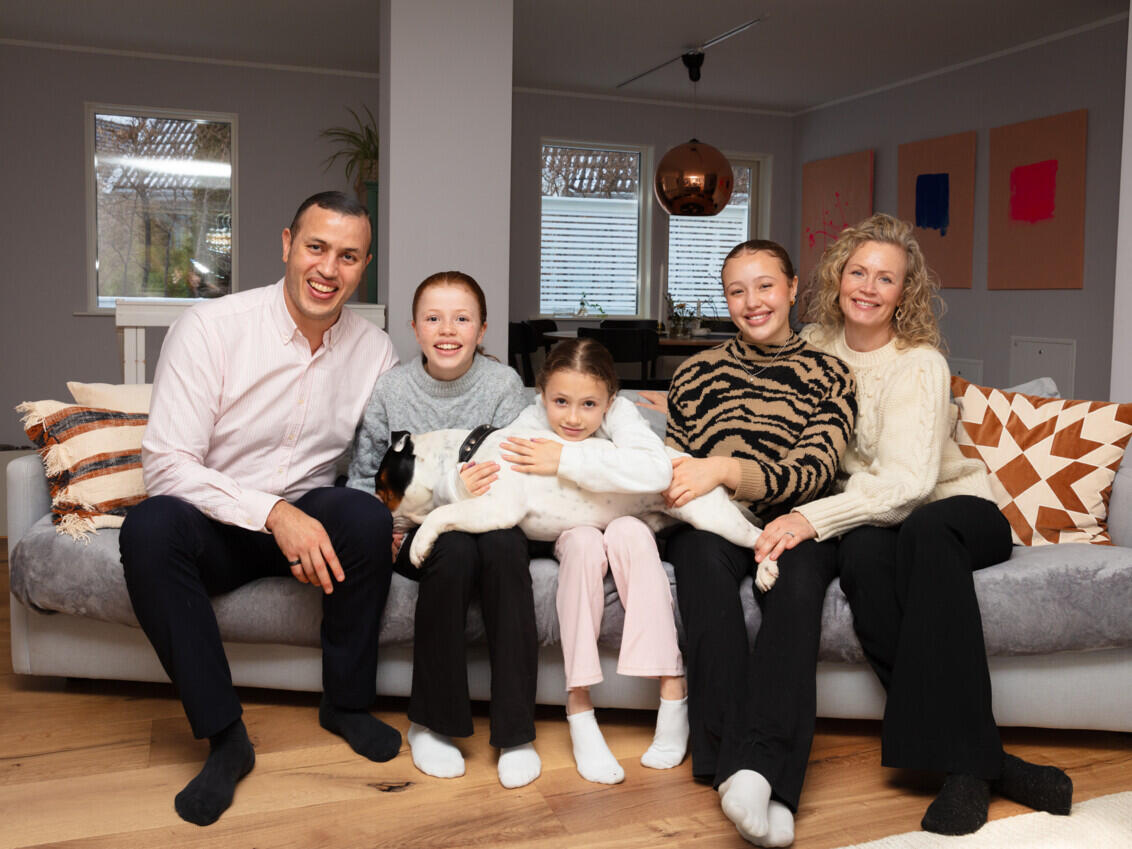 Familien Jallow sidder i en grå sofa i stuen.