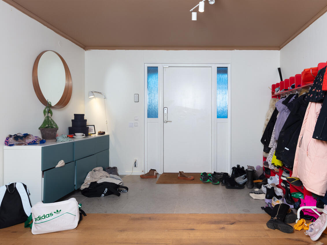 Entréen, som den så ud før, med en rød børnehavehylde og en blå kommode.