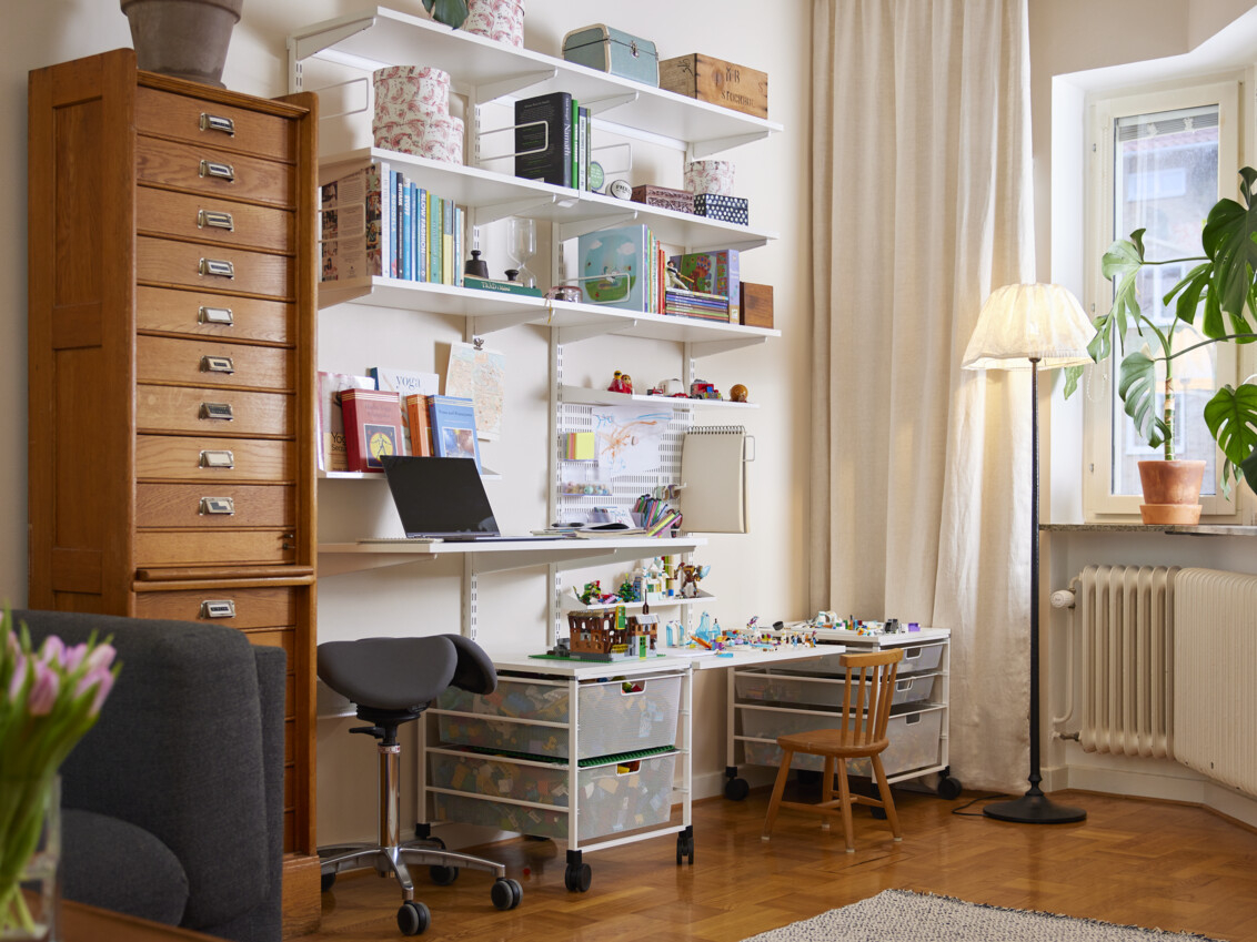 Olohuone, jossa on seinälle ripustettu Classic by Elfa -kotitoimisto, jossa osa tilasta on omistettu lapsille.