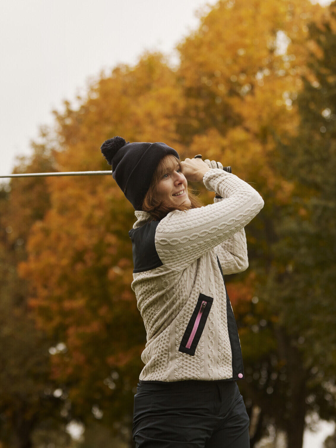Sara hits a shot with the golf club over her shoulder
