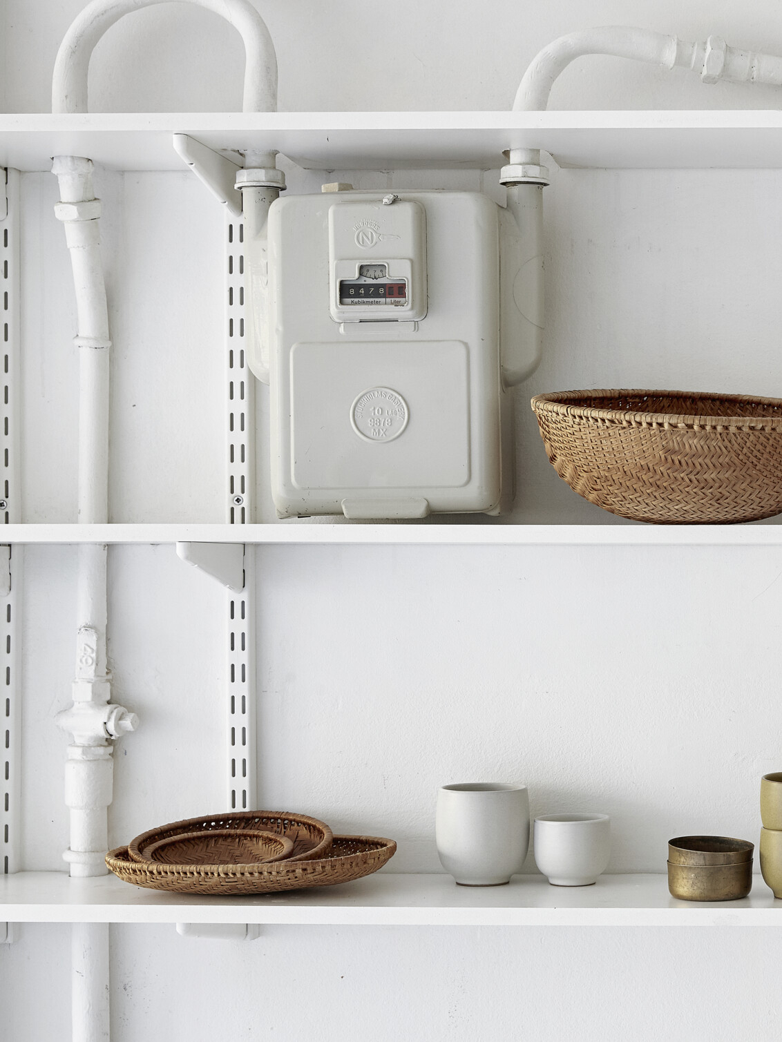 Hyllor från Sparring by Elfa i vitt som är byggda runt ett elskåp.