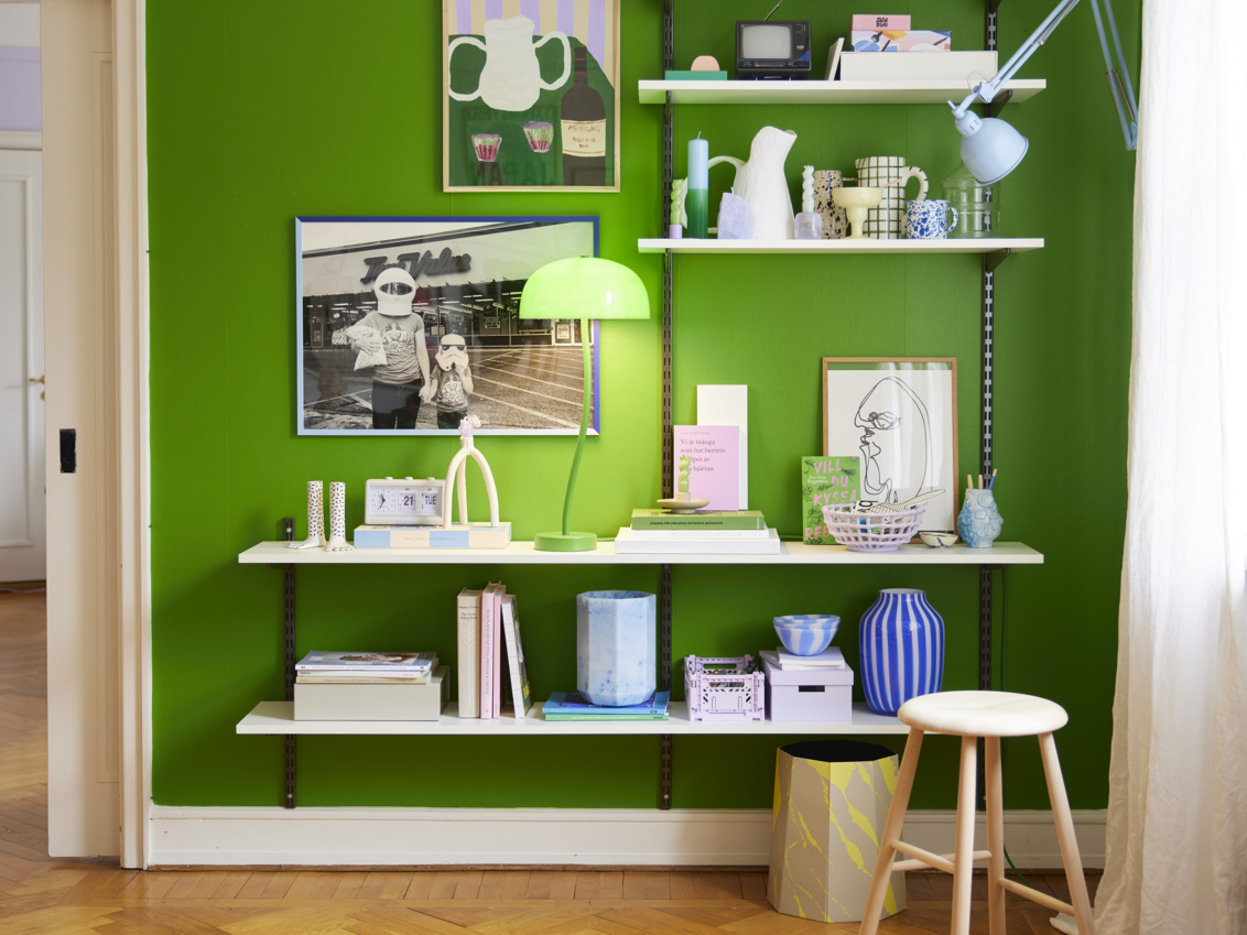An Elfa shelf with grey wallbands and brackets, and white melamine shelves against a lime green wall.