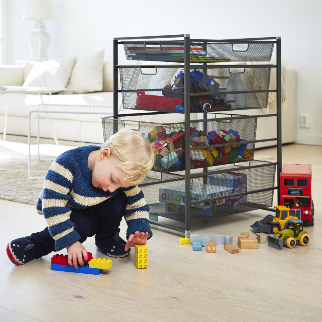 Chłopiec bawi się Duplo przy szarym systemie koszy Classic by Elfa z wysuwanymi siatkowymi koszami.
