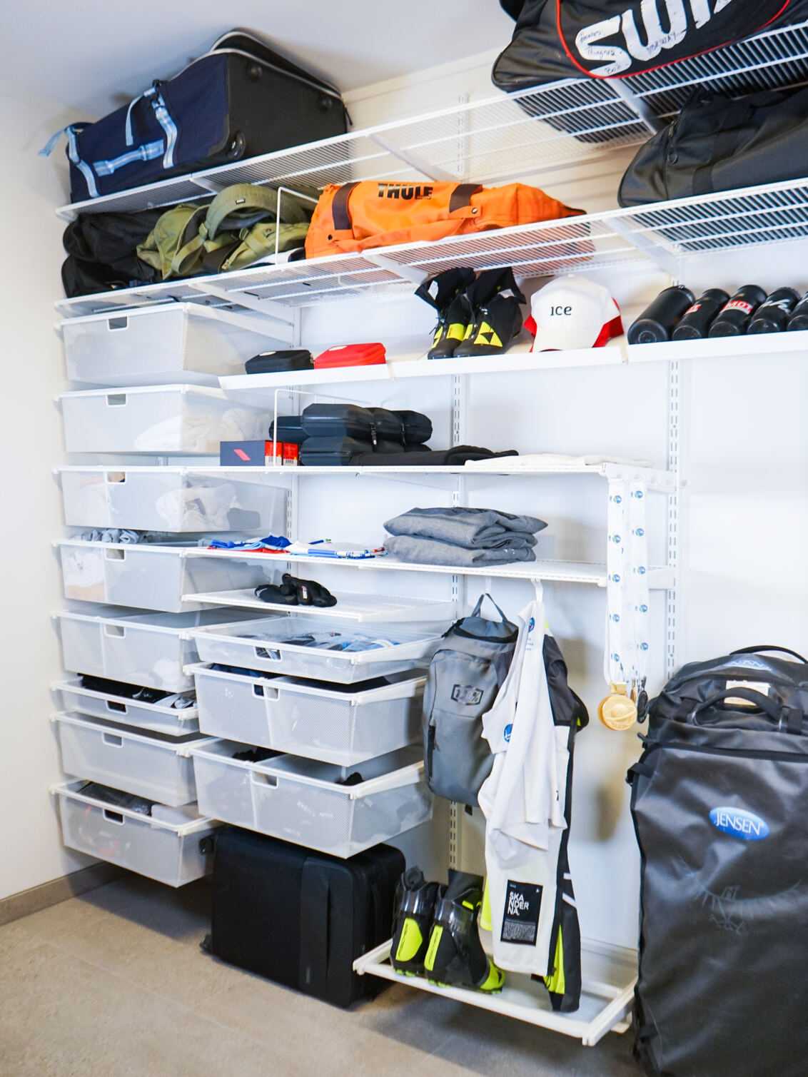 Oppbevaringsrom med Classic by Elfa oppbevaring i hvitt der det oppbevares sportsutstyr og vesker.